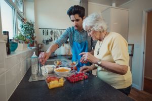 THS worker assists a senior woman to prepare a meal.