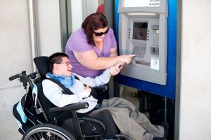 Attendant Outreach - A woman helps a man use a bank machine